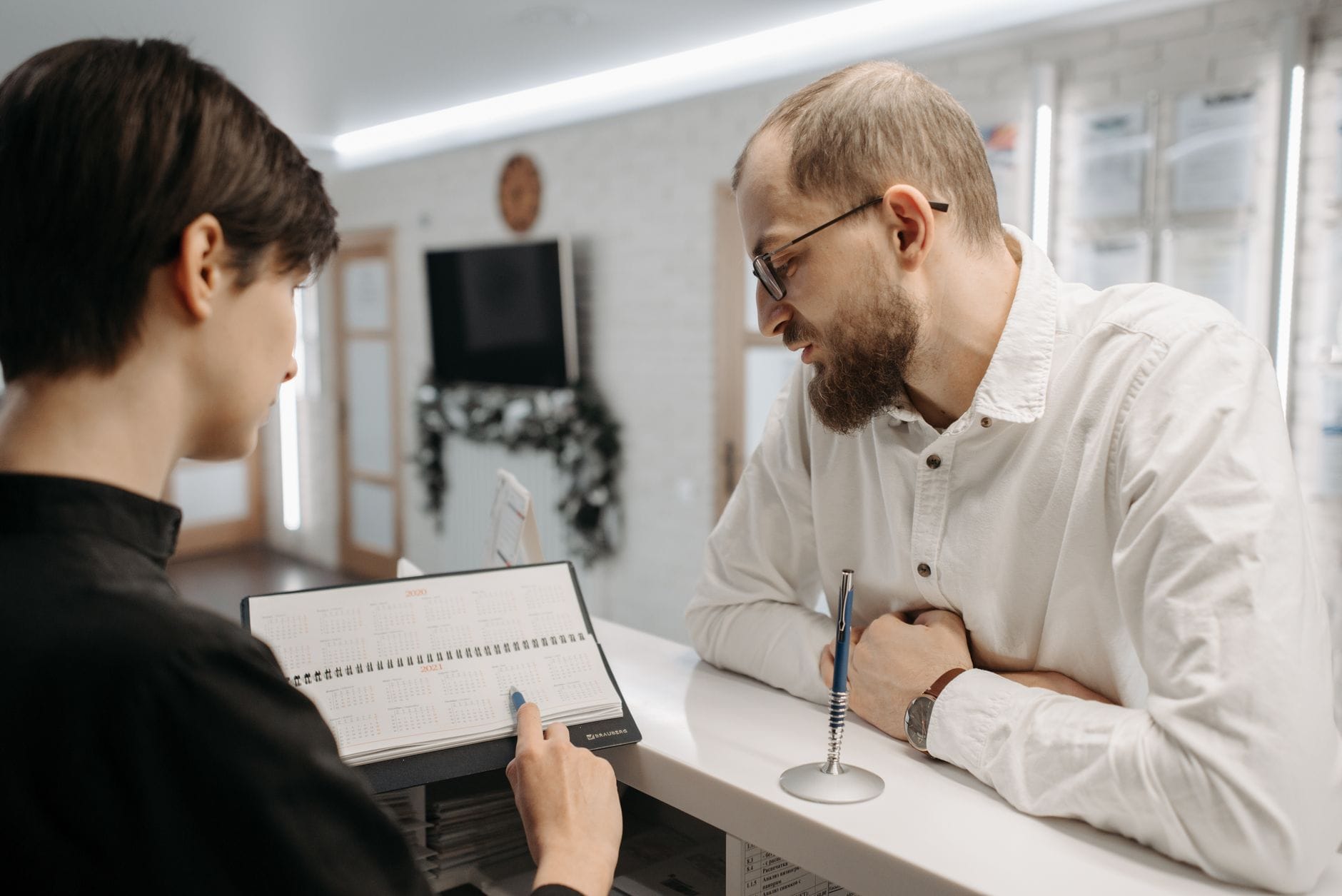 Reception staff reviewing an appointment schedule with a patient