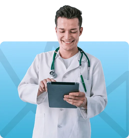 Smiling male doctor in white coat with stethoscope using a tablet against a blue background