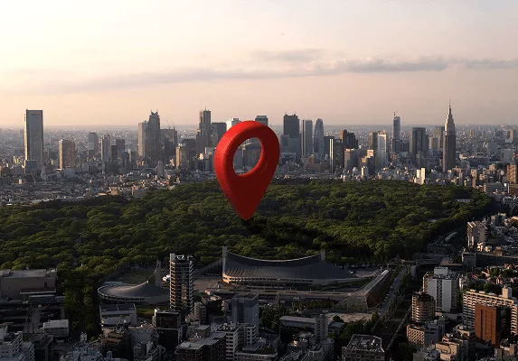 Red map location pin over an aerial view of a city skyline and large green park