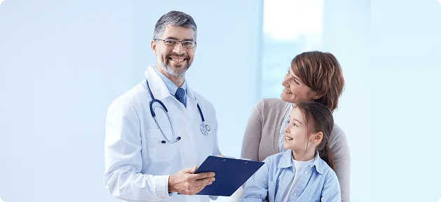 Smiling doctor in a white coat holding a clipboard beside a mother and young daughter