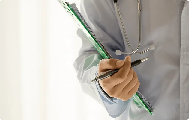 Clinician in a white coat holding a pen and green clipboard, stethoscope around the neck