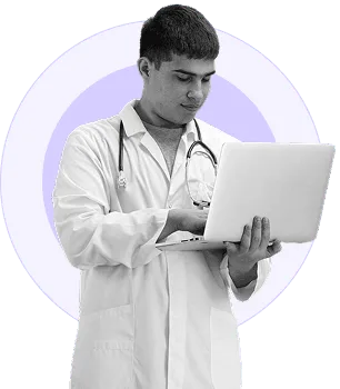 Young man in white coat looking at an open laptop, in black and white