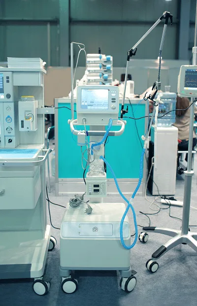 Mobile medical equipment unit with monitor screen, blue tubing and IV stand in an equipment hall