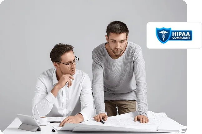 Two men reviewing large documents on a desk