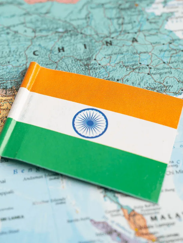 Small Indian tricolor flag lying on a printed world map