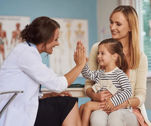 Female doctor giving a young girl a high five while the mother looks on