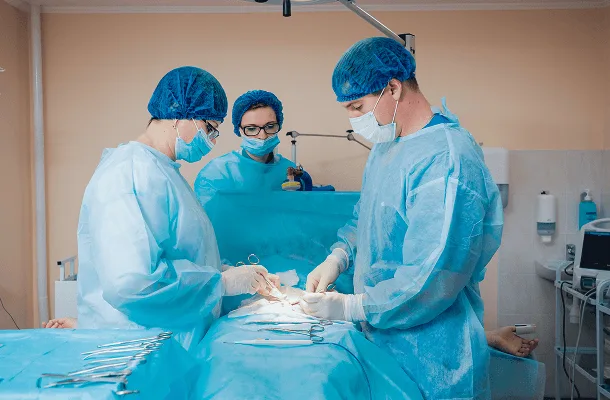 Surgical team in masks, caps and gowns operating on a patient in an operating room