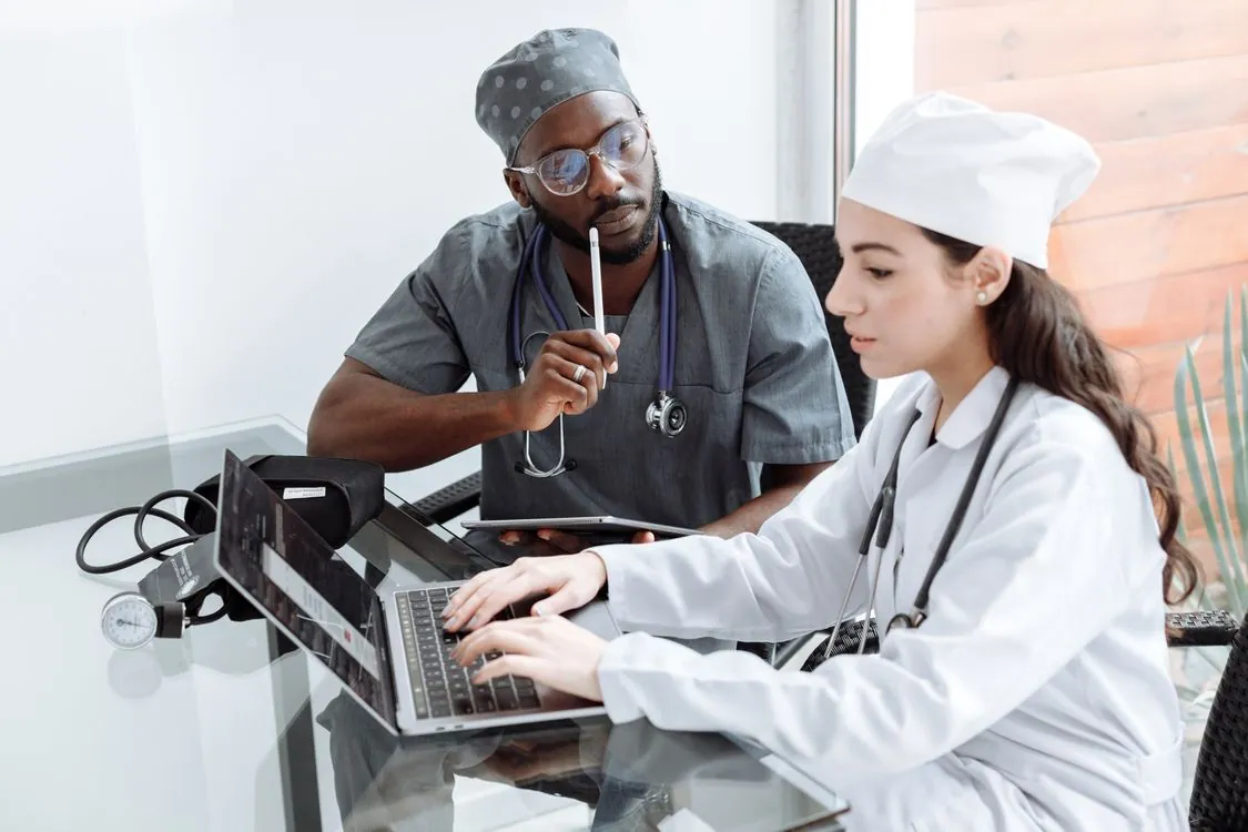 Two healthcare professionals reviewing information on a laptop