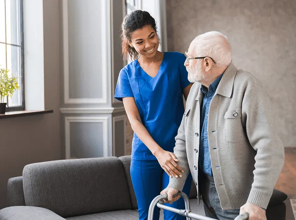 Nurse assisting an older patient who uses a walker
