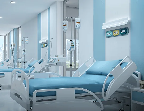 Hospital ward with empty beds, blue linens, IV stands and wall-mounted outlets