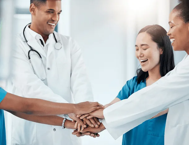 Smiling group of healthcare workers stacking their hands together in a team huddle