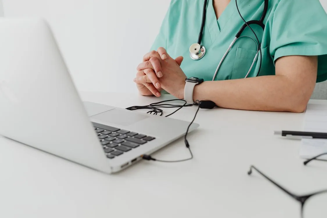 Healthcare professional in scrubs at a laptop