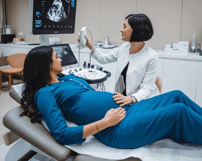 Clinician performing an ultrasound scan on a pregnant patient lying on an exam table