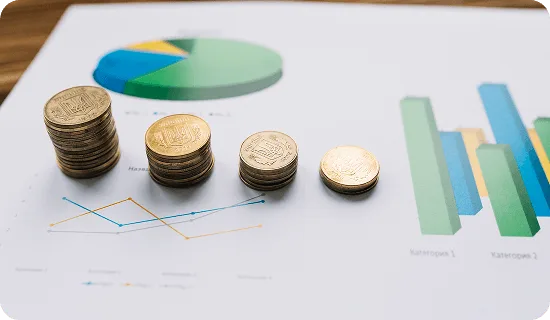 Stacks of coins on printed pie, bar and line charts