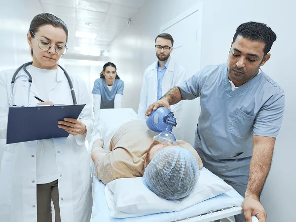 physician image 59444 webp Medical team around a patient on a gurney while one staff member squeezes a bag valve mask