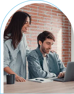 Smiling woman and man looking at a laptop together in a brick-walled office