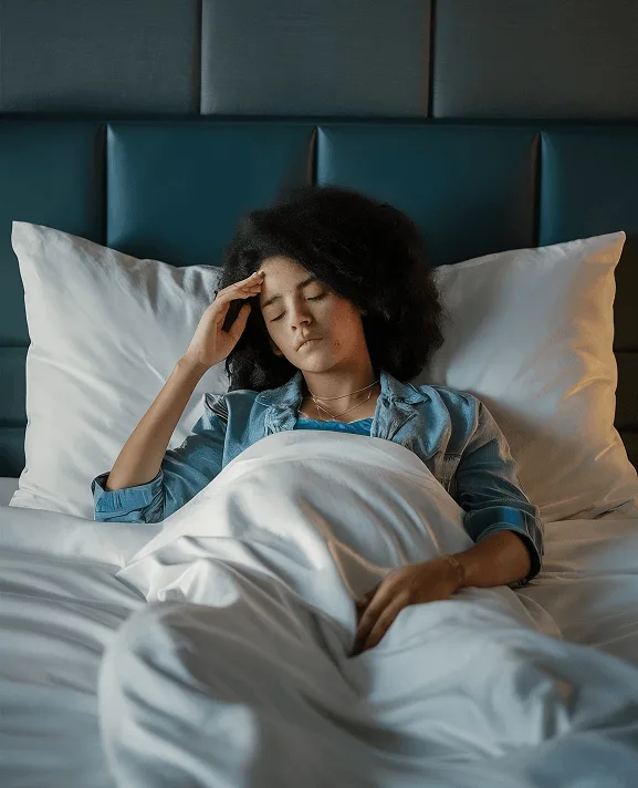 Woman lying in bed with her hand on her forehead and eyes closed