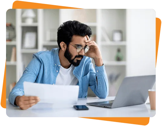 wound-care image 61349 webp Bearded man with glasses resting his head on his hand, looking worried at a paper and laptop